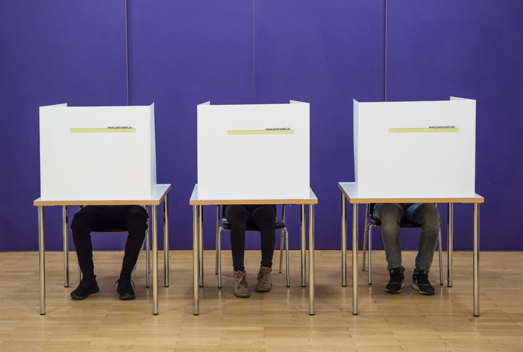 Drei Wahlkabinen in einer Reine vor einem lila Hintergrund