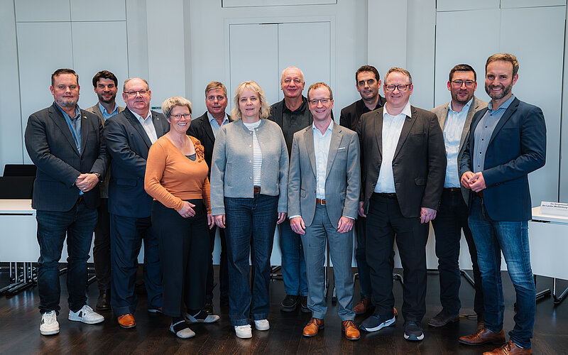 Eine Gruppe Abgeordneter steht in einem Konferenzraum