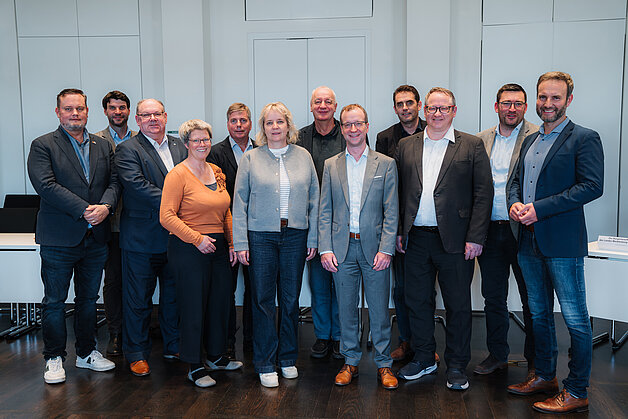 Eine Gruppe Abgeordneter steht in einem Konferenzraum