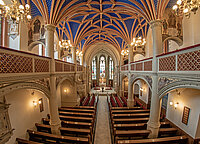 Prächtige Innenansicht der Schlosskirche Schwerin mit blau-goldenem Sternengewölbe, Buntglasfenstern und hölzernen Kirchenbänken.