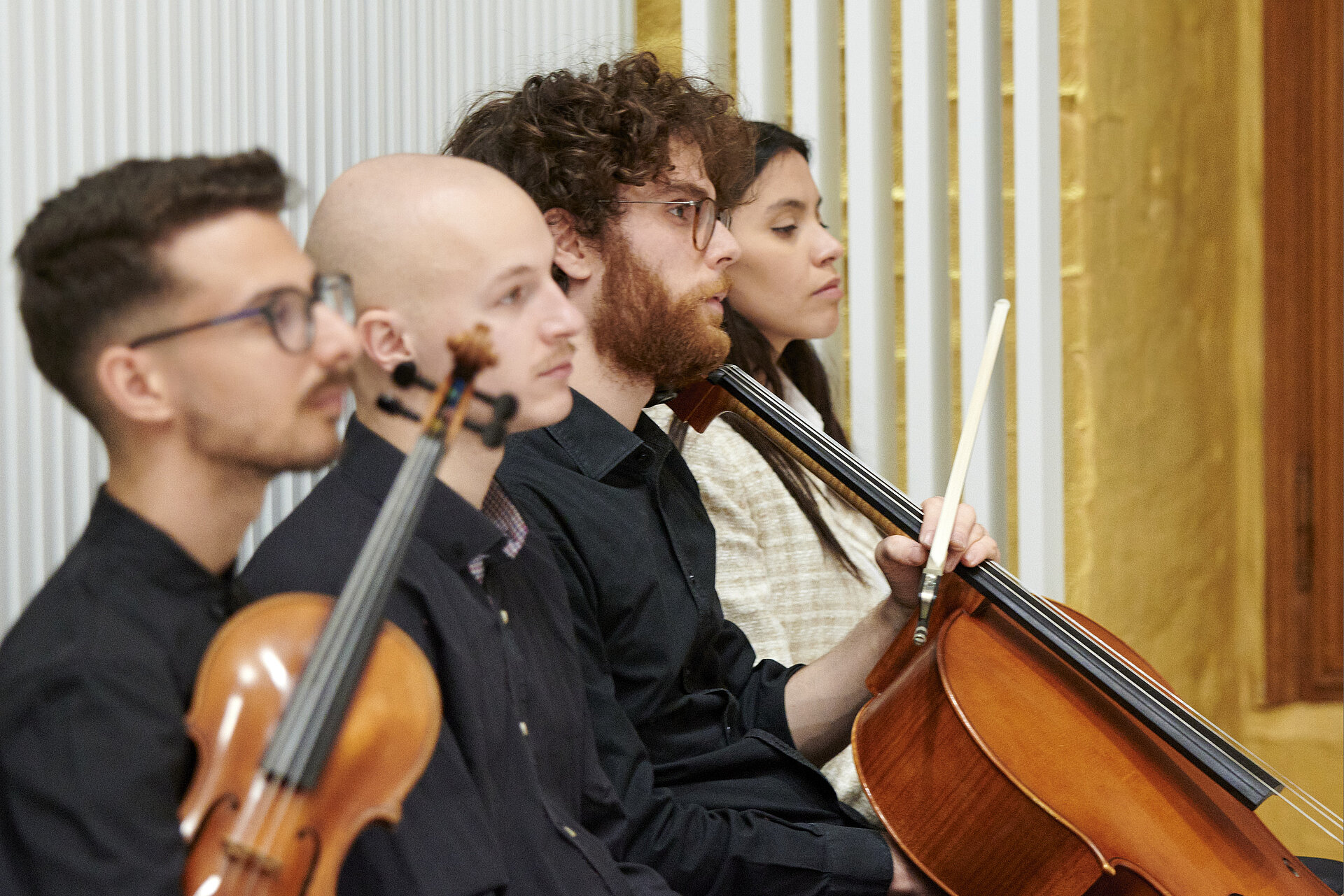 Vier junge Musikerinnen und Musiker mit Streichinstrumenten sitzen konzentriert im Plenarsaal des Landtages Mecklenburg-Vorpommern.