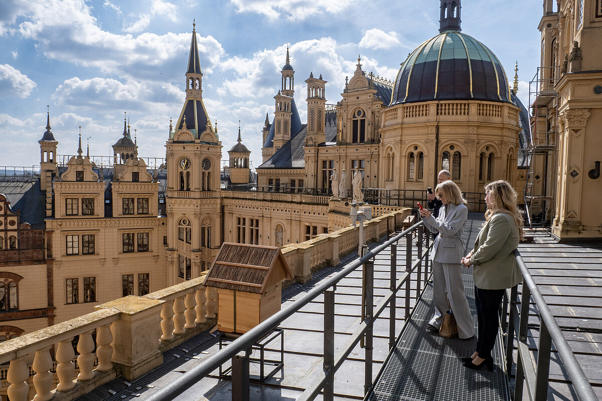 Zwei Frauen auf dem Dach eines historischen Schlosses, es sind zahlreichen Kuppeln und Türme zu sehen.