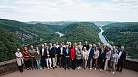Gruppenfoto auf einer Aussichtsplattform mit Blick auf bewaldete Flussschleife