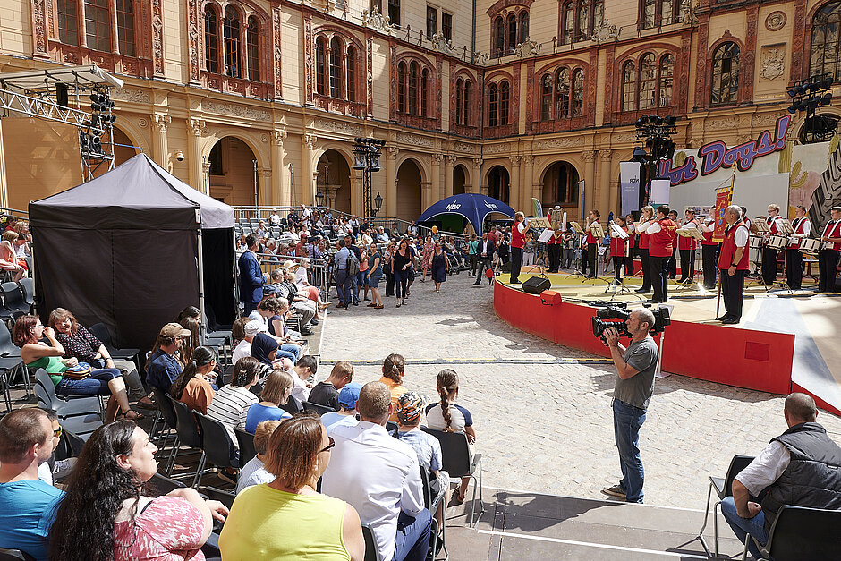 Menschen haben sich um eine Bühne im Schlossinnenhof versammelt