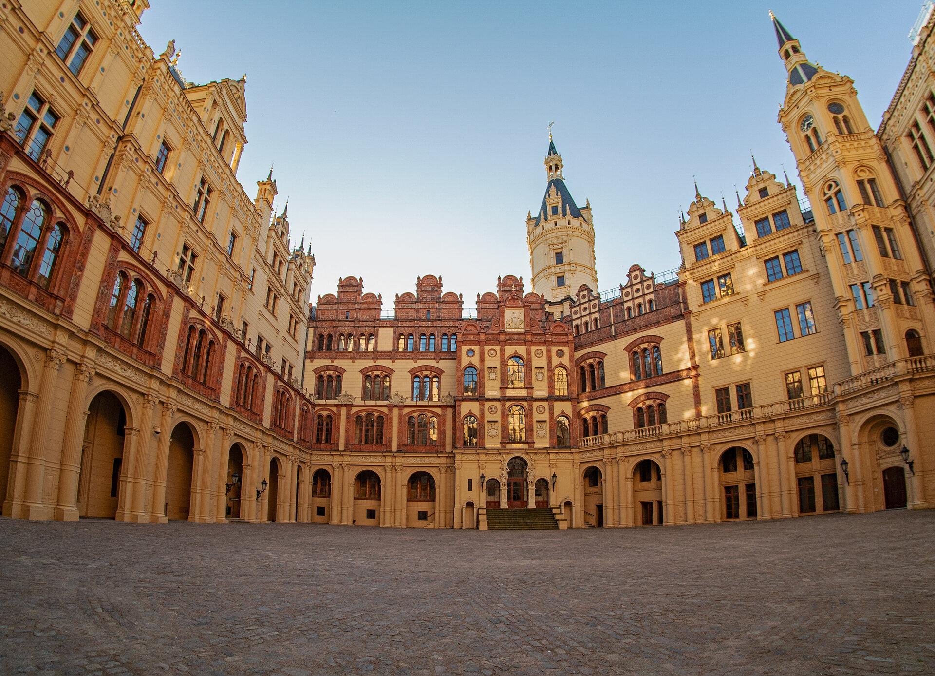 nnenhof des Schweriner Schlosses mit historischer Fassade, Rundbögen und zentralem Turm unter klarem, blauem Himmel