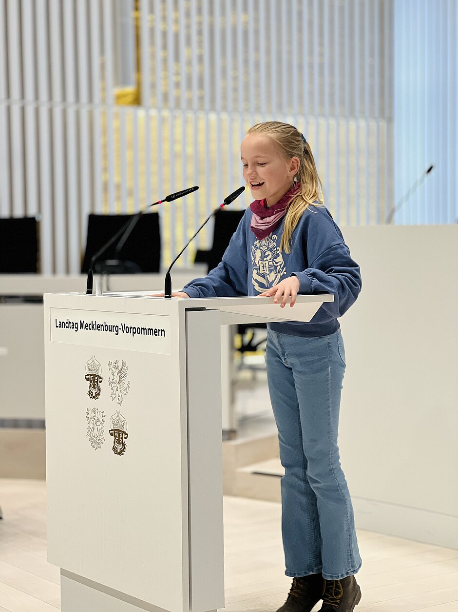 Schülerin einer Besuchergruppe am Pult im Plenarsaal des Landtags Mecklenburg-Vorpommern während der Simulation einer Debatte