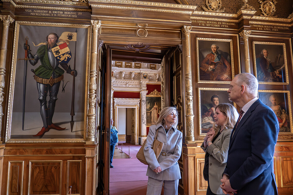 Zwei Frauen und ein Mann in den historischen Räumlichlichkeiten eines Museum, eine Gemäldegalerie mit Bildern von Herzögen ist zu sehen