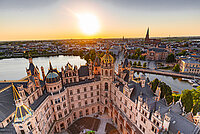 Luftaufnahme des Schweriner Schlosses bei Sonnenuntergang mit Blick über die Altstadt und den Schweriner See.