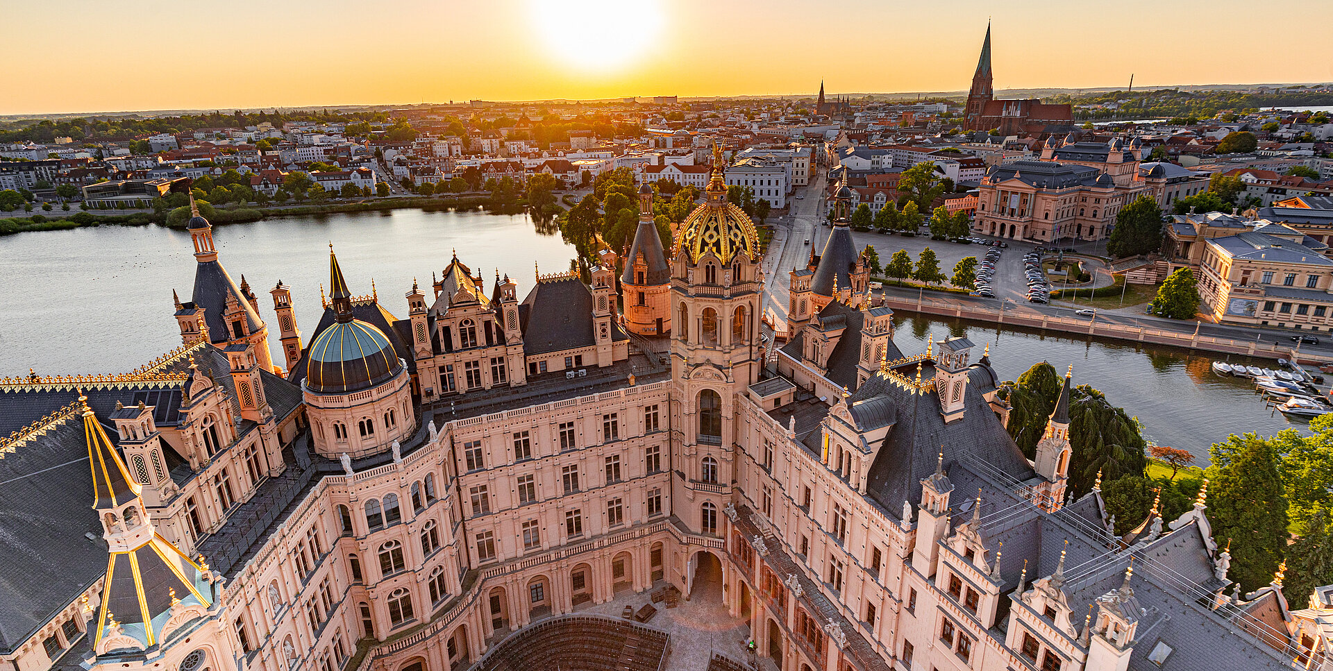 Luftaufnahme des Schweriner Schlosses bei Sonnenuntergang mit Blick über die Altstadt und den Schweriner See.