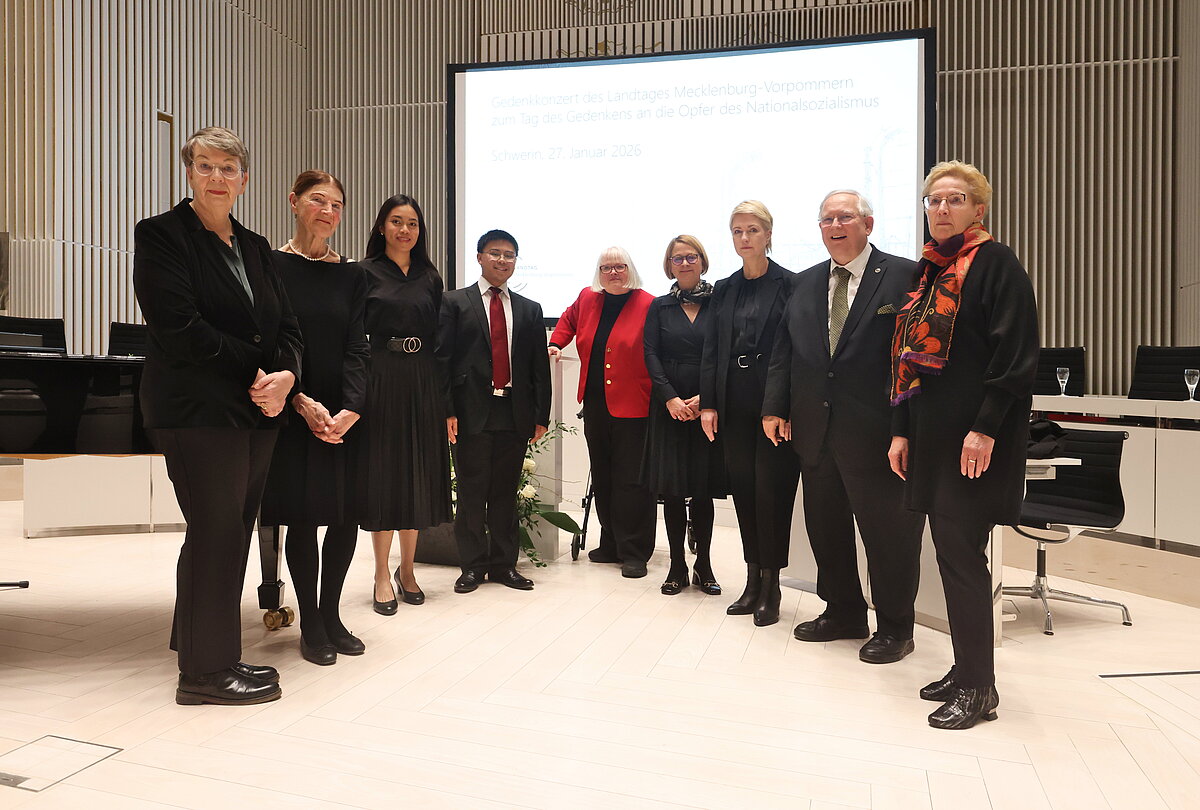 Gruppenfoto mehrerer Personen im Plenarsaal des Schweriner Schlosses vor dem Rednerpult