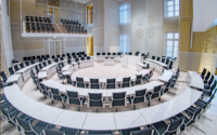 Moderner Plenarsaal des Landtags Mecklenburg-Vorpommern mit weißen Tischen und schwarzen Stühlen in halbrunder Anordnung