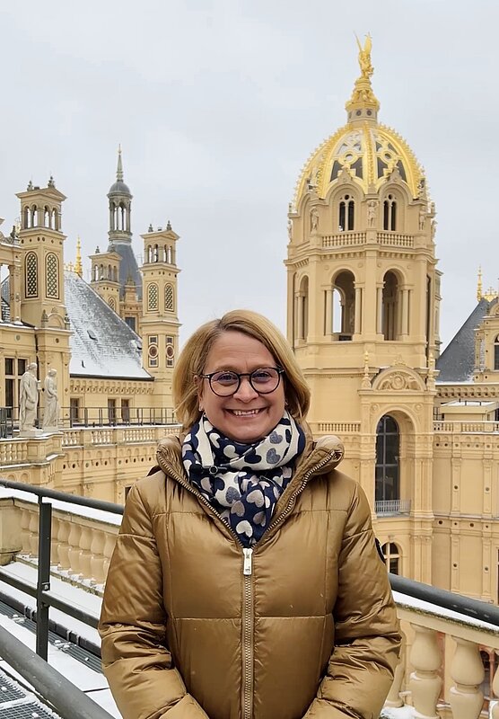 Frau in Winterjacke steht auf dem Dach eines Schlosses