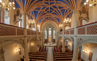 Prächtige Innenansicht der Schlosskirche Schwerin mit blau-goldenem Sternengewölbe, Buntglasfenstern und hölzernen Kirchenbänken.