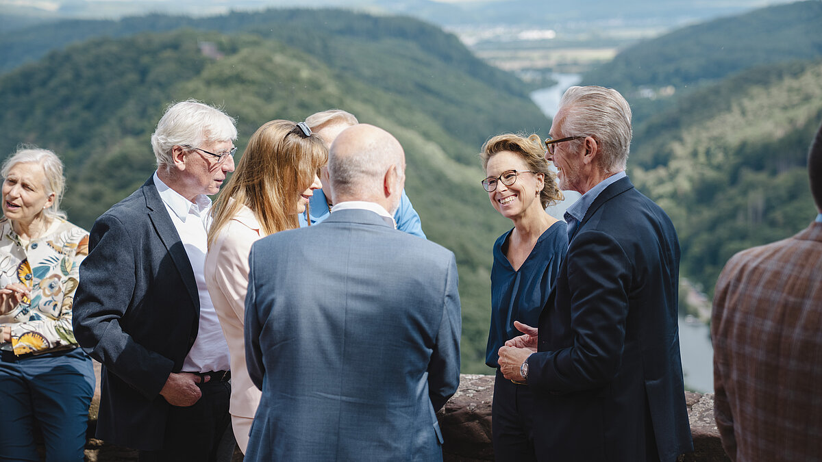 Gruppe von Menschen steht an einer Aussichtsplattform mit Blick auf bewaldete Hügel