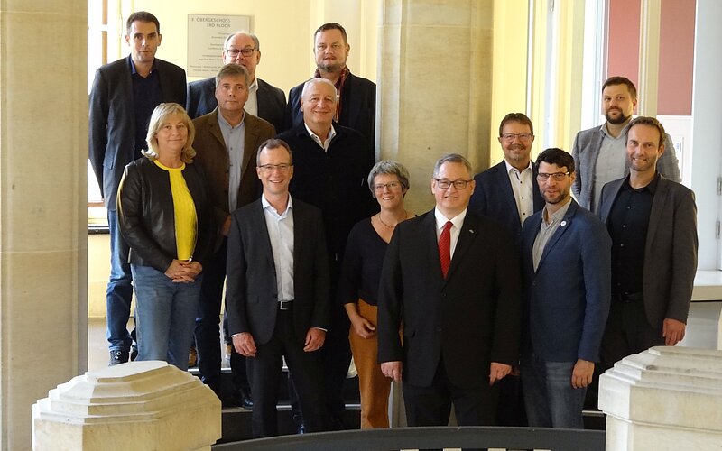 Mitglieder des Finanzausschusses stehen als Gruppe auf der Roten Marmortreppe vor dem Plenarsaal